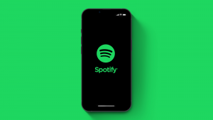 緑色の背景にスマートフォン iPhone 13 Pro の Spotify (SPOT) アプリが表示されます。