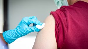 A nurse cleans a patients are with a cotton ball after administering a flu shot