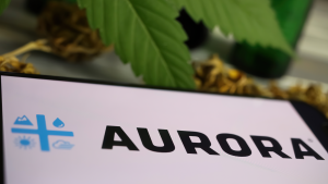 Detailní záběr na obrazovku mobilního telefonu s logem kanabinoidní společnosti Aurora Cannabis (ACB, rozmazaný list marihuany (zaměřte se na levou část písmene R uprostřed)