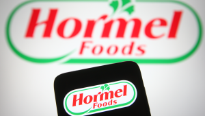 Hormel Foods のロゴは、携帯電話の画面の後ろにあるラップトップの画面にも表示され、ロゴも表示されています。 HRL株。