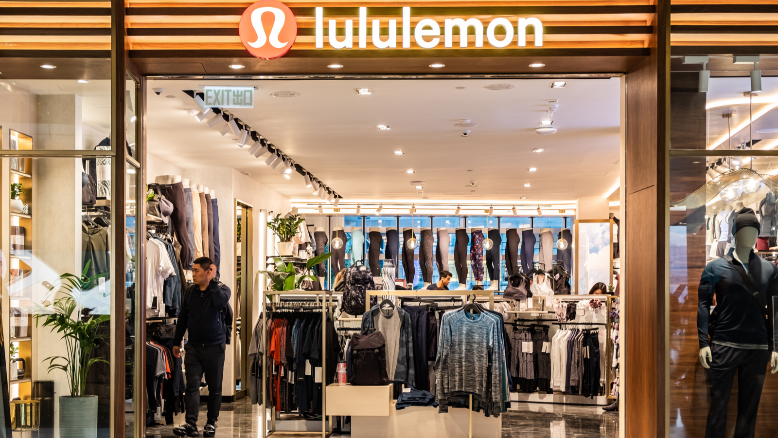 Lululemon storefront in a mall. People shop inside the store among the clothes. LULU stock.