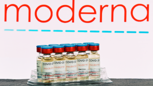 Moderna (MRNA) research Coronavirus (Covid 19) vaccine. Row of vaccine bottles with blurred Moderna company logo on background.