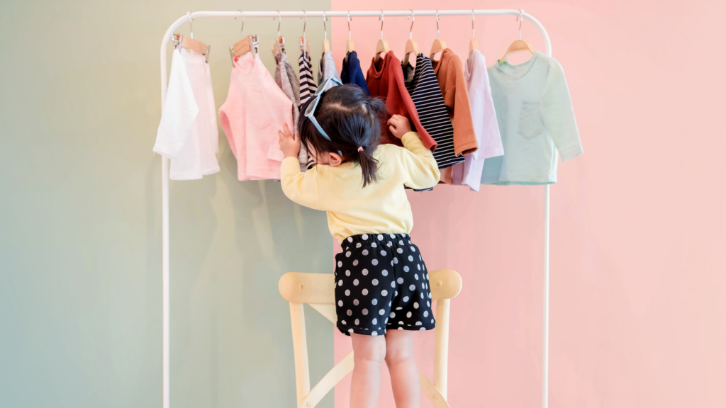 Soft Focus of a Two Years Old Child Choosing her own Dresses from Kids Cloth Rack, Kidpik (PIK)