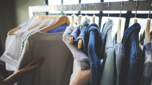 apparel stocks: a person looking at several pieces of clothing hanging on a rack