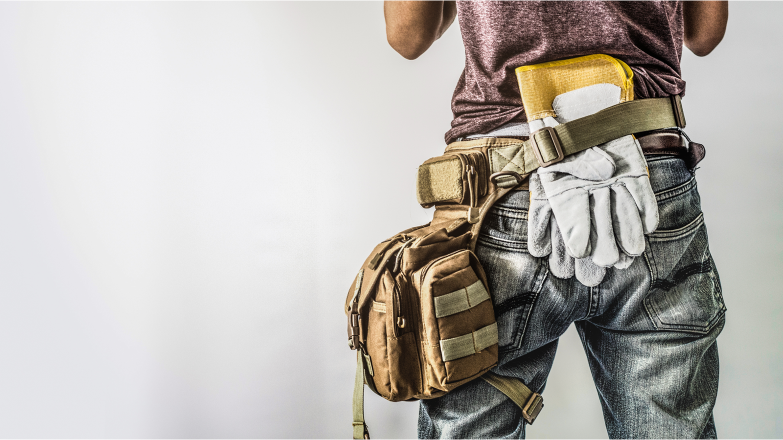 A man wearing dirty clothes with a tool belt around his waist.