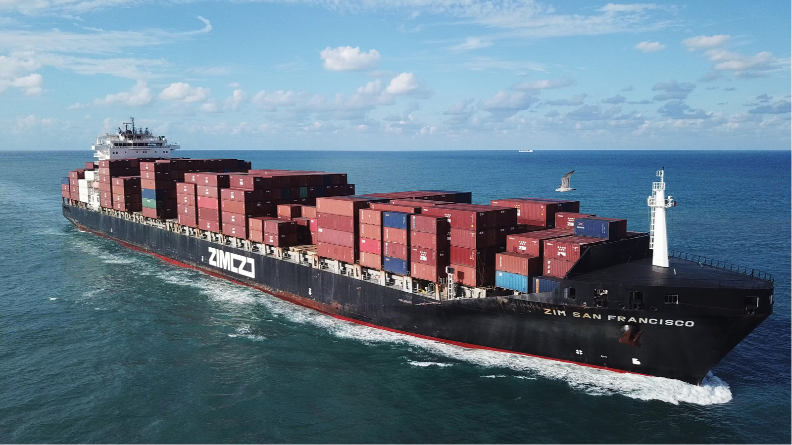 A large ULCV container ship underway, sails on open water fully loaded with containers and cargo - the ZIM San Francisco, representing zim stock.