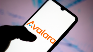 Avalara logo displayed on a phone screen in front of a tie-dye background. AVLR stock.
