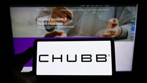 Person holding cellphone with logo of Swiss insurance company Chubb Limited on screen in front of business webpage. CB stock.