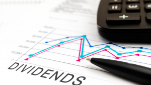 A photo of a paper with a chart and the word "Dividends" written on it, with a pen and calculator resting on top of it.