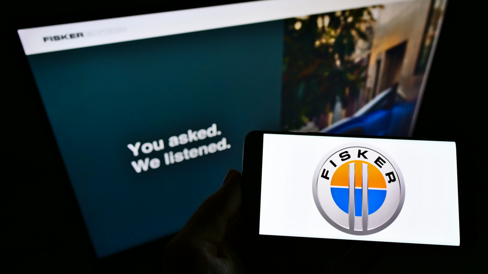 Person holding smartphone with logo of American electric vehicle manufacturer Fisker Inc. on screen in front of website. FSR stock.