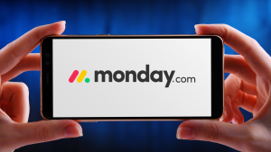 Monday.com (MNDY) logo displayed on smartphone held by two hands