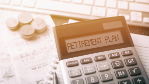 Coins stacked next to a calculator that says "retirement plan." Retirement stocks. Retirement Stocks to Buy