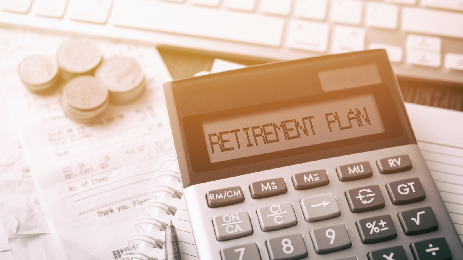 Coins stacked next to a calculator that says "retirement plan." Retirement stocks.