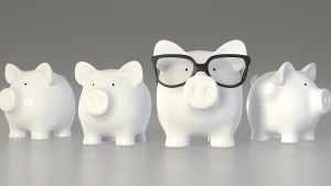An image of four piggy banks, one with glasses on to represent smart money in investing