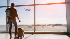 Plane travel. Man standing in airport waiting for flight. travel stocks to buy