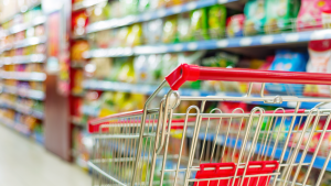 An image of an empty grocery cart in a grocery store aisle, representing consumer goods.