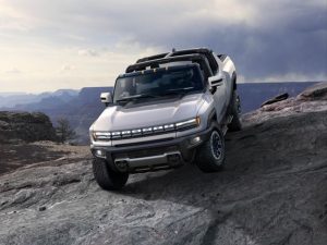An image of the electric Hummer parked on a boulder with mountains in the background; EV