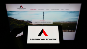 American Tower Corporation logo on a smartphone with the website in the background on a computer screen. AMT stock.
