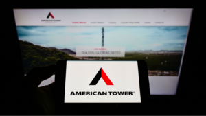 Logo d'American Tower Corporation sur un smartphone avec le site Web en arrière-plan sur un écran d'ordinateur.  Actions AMT.