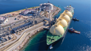 Aerial drone photo of LNG (Liquified Natural Gas) tanker anchored in small LNG industrial islet of Revithoussa equipped with tanks for storage, Salamina, Greece.