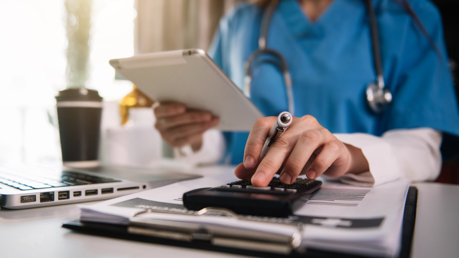 RSLS Stock. Doctor or physician calculating a patients medical bills at a desk. Medical bills, health costs, health expenses.