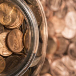 Pennies in a jar on top of a background of blurred pennies. Penny stocks.