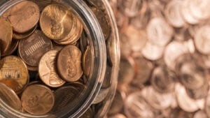 Pennies in a jar on top of a background of blurred pennies. Penny stocks.