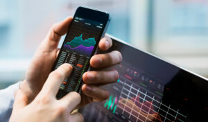 a man checks a stock's performance with a computer in the background