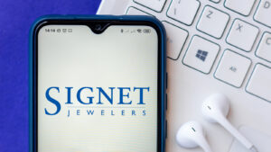 Signet Jeweler logo on a smartphone displayed on top of a keyboard with headphones. SIG stock.