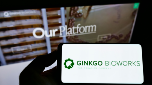 Web ページの前の画面に、アメリカのバイオテクノロジー企業 Ginkgo Bioworks Inc. のロゴが付いた携帯電話を持っている人。 電話のディスプレイに焦点を当てます。 無修正写真。 DNAストック