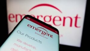 A mobile phone displays the website for Emergent Biosolutions (EBS)