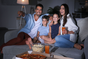 Happy family watching TV on sofa at night. Family entertainment stocks like CSSE
