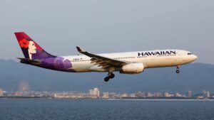 A Hawaiian Airlines plan flying over the water.