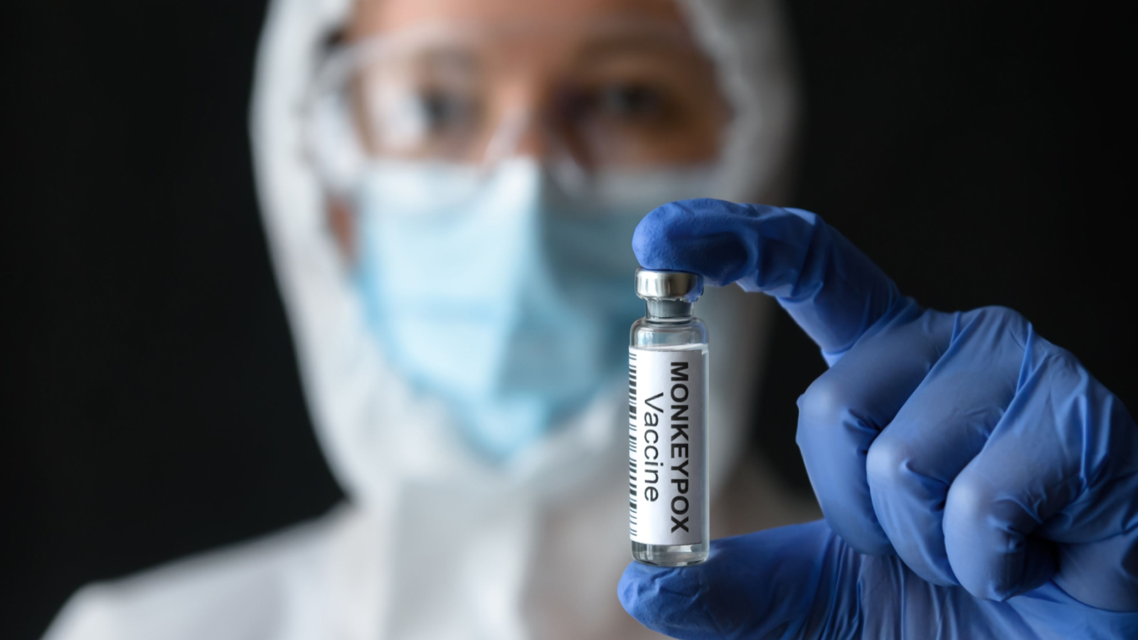 Monkeypox vaccine in doctors hand, medical female worker in personal protective equipment (PPE) shows bottle for shot from smallpox representing SIGA stock.