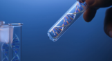 DNA molecule in glass tube in hand of scientist on blue. Invitae does genetic testing. NVTA stock