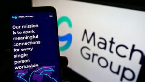 MTCH stock: the Match group logo on a computer screen with a phone displaying its site