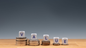 Symbol for decreasing value. Dice placed on stacks of coins form the word "value." Cheap Value stocks.