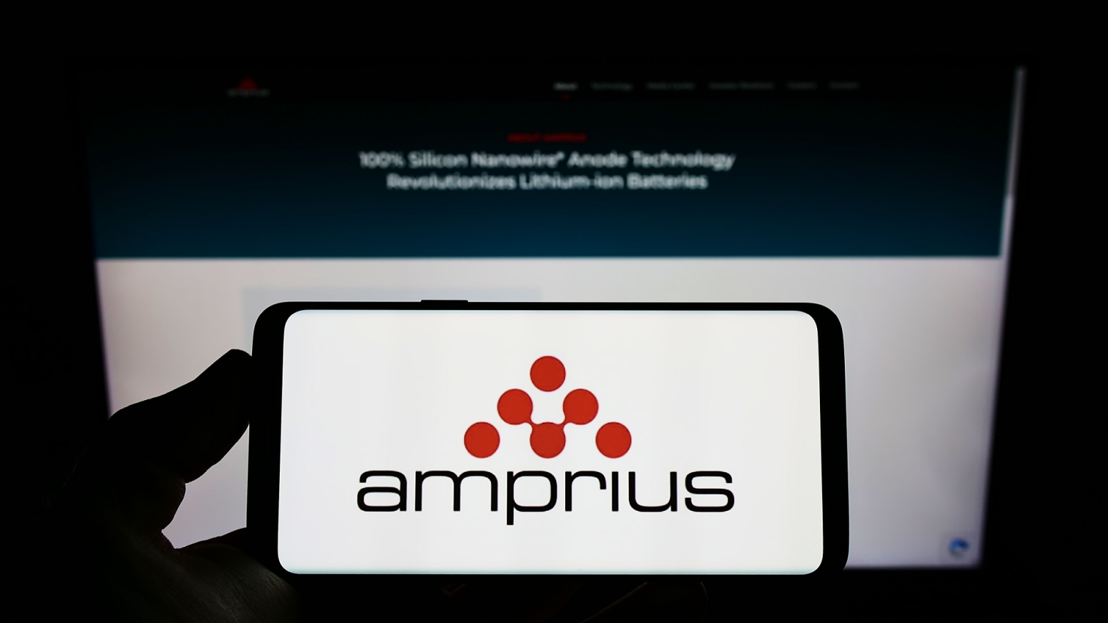 Person holding mobile phone with logo of American company Amprius Technologies (AMPX) Inc. on screen in front of web page. Focus on phone display. Unmodified photo.