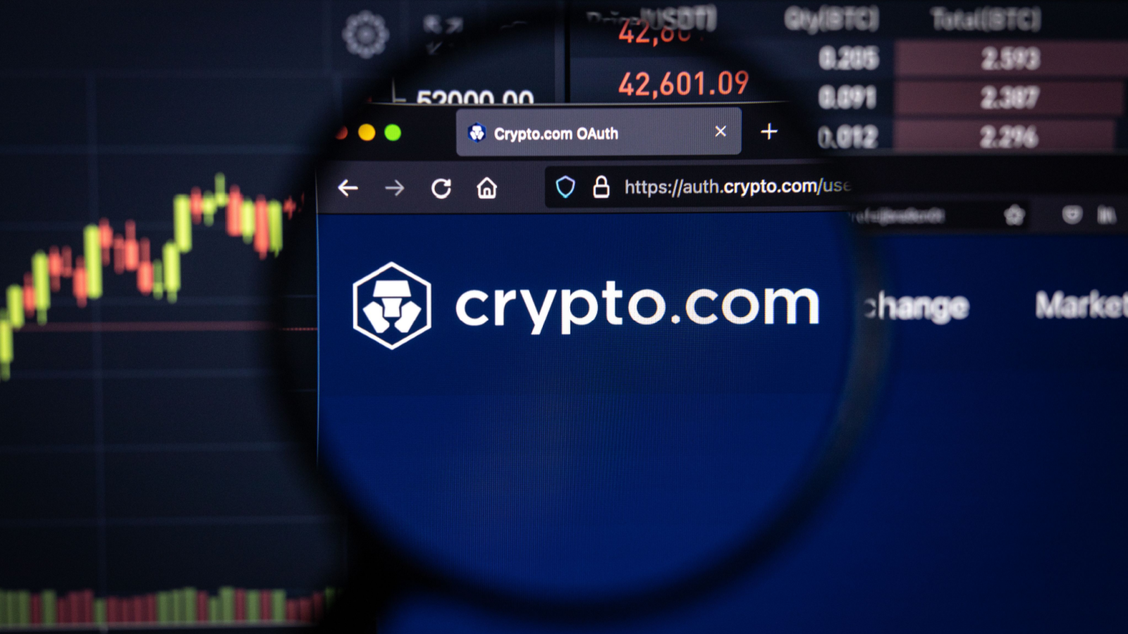 Cronos Price Predictions Crypto.com company logo on a website with blurry stock market developments in the background, seen on a computer screen through a magnifying glass.
