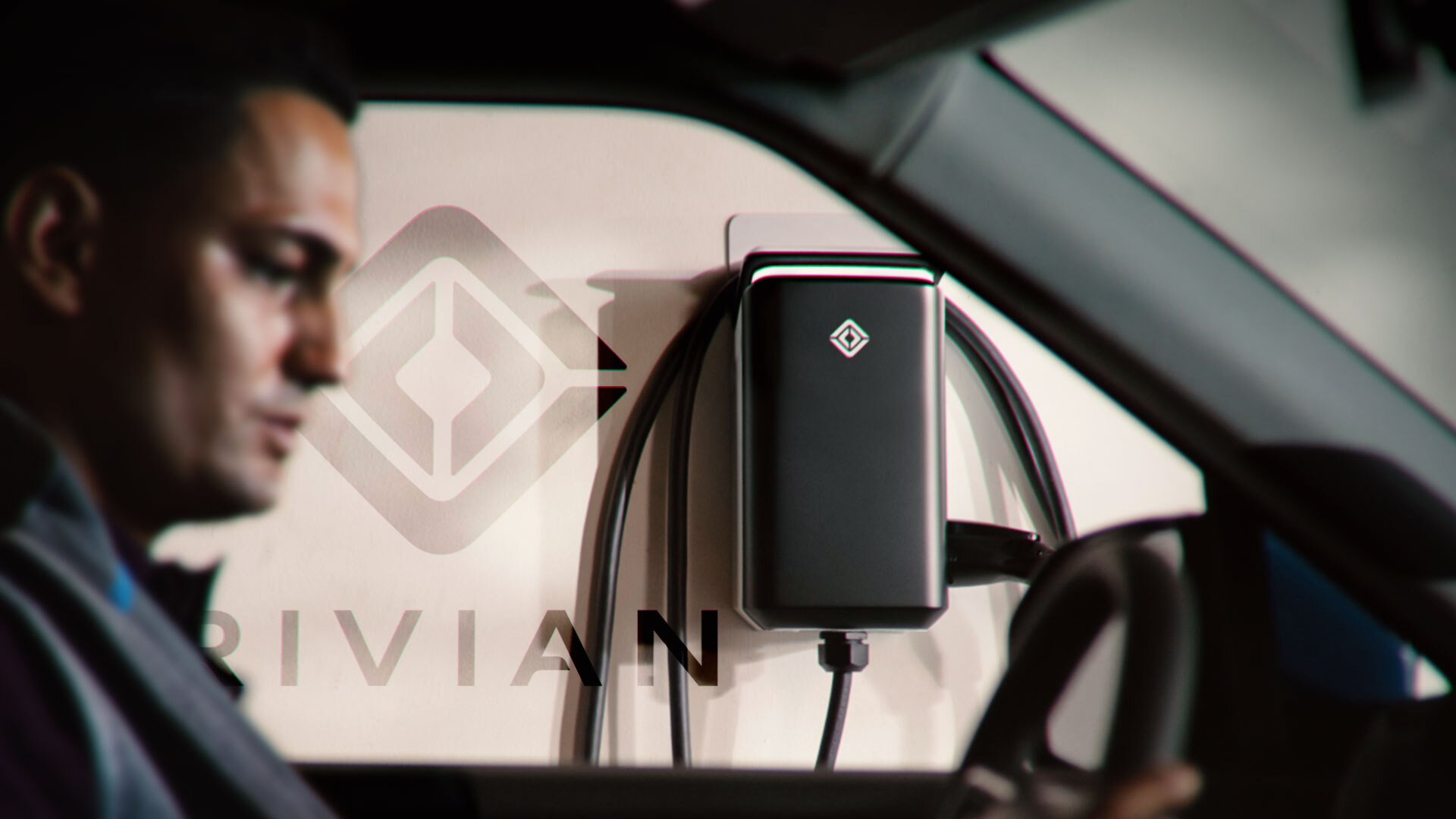 An image of Luke sitting in a car looking forward, Rivian on the wall behind him; Rivian stock