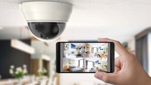 A hand holding a smartphone with various camera angles up against a home security camera.