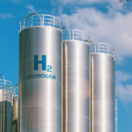 An image of hydrogen fuel silos standing against a blue sky