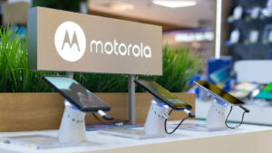 Motorola smartphones are shown on display in electronic store. The brand logo is in the background.