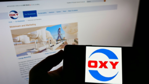 Person holding a cell phone with the logo of the American company Occidental Petroleum Corp.  (OXY) on the screen in front of the website.  Focus on the phone screen.  Unedited photo.