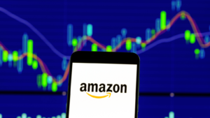 An image illustrating the Amazon logo on a phone in front of a stock chart to symbolize Amazon stock