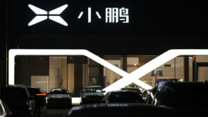 Xpeng (XPEV) car dealership at night with white company logo on display above EVs