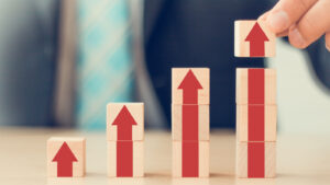 A businessman's hand arranging wooden cube blocks to represent growth stocks.