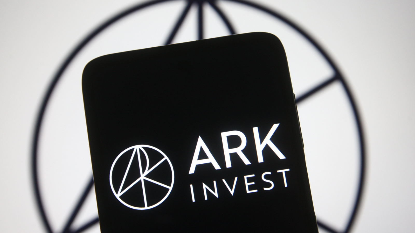 Logo for Ark Invest displayed on phone with logo in background as well, symbolizing Cathie Wood stocks