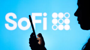 Silhouette of person holding mobile phone with SoFi (SOFI) logo shown in background