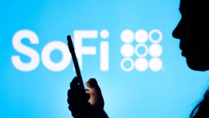 Silhouette of a person holding a mobile phone with the SoFi logo (SOFI) visible in the background